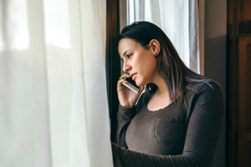 Person looking out of a window while on a phone 