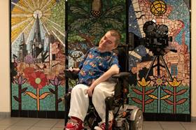 Customer Andy Walker in his wheelchair in front of a mural 