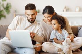 family sitting on sofa round a laptop