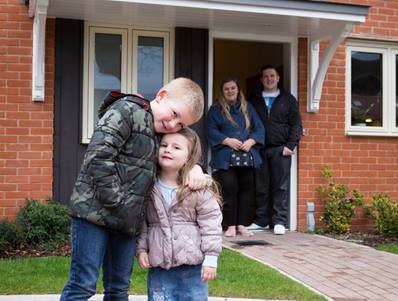 Family outside their home children hugging